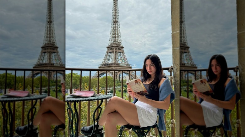 Haley Pham reading on a balcony in front of the Eiffel Tower