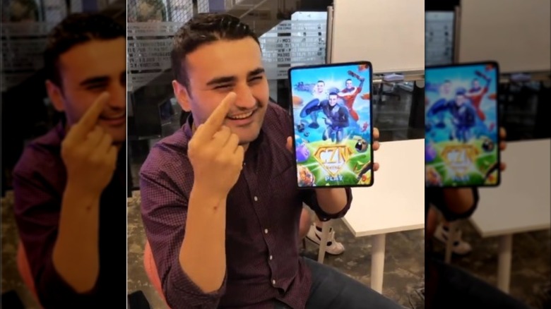CZN Burak, also known as Burak Ozdemir, holds up a tablet showing his mobile game