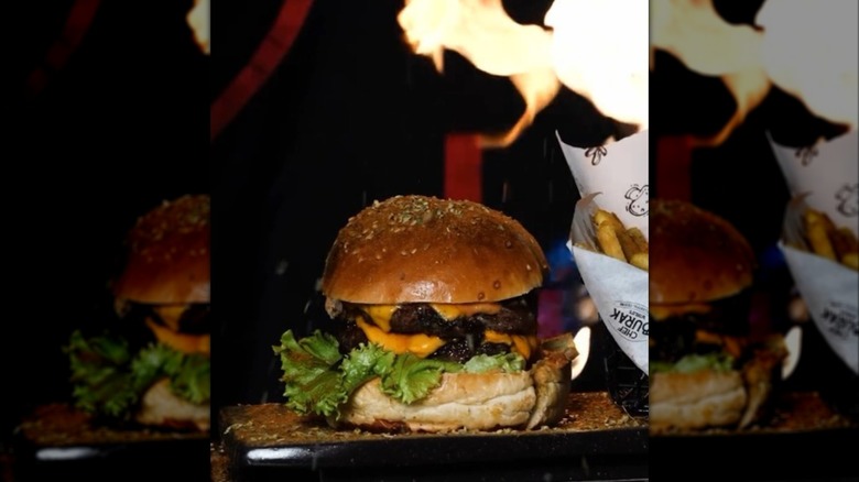 A CZN Burak burger with a side of fries and flames in the background