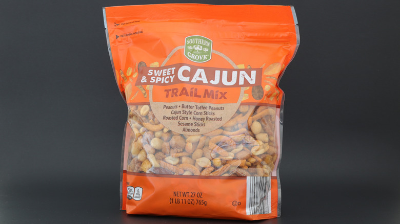 An orange bag of Southern Grove Sweet & Spicy Cajun Trail Mix on a dark gray background