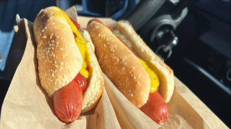 Two Costco hot dogs with mustard and relish in car