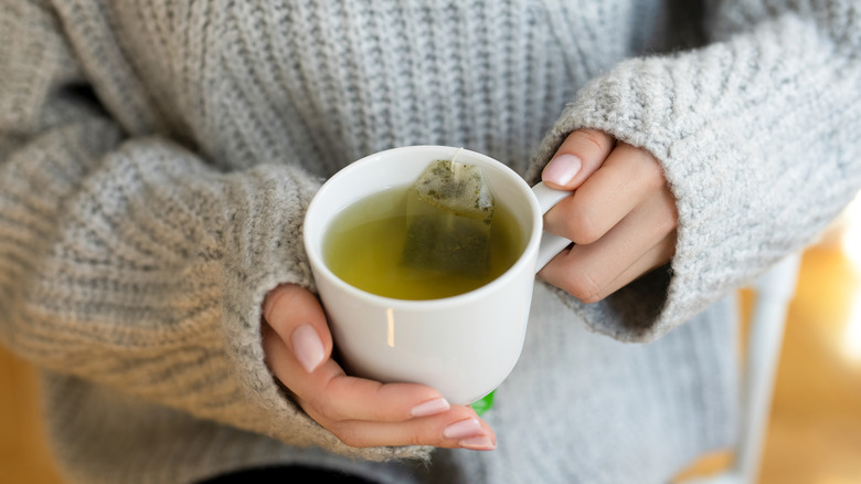 Person holding a cup of green tea