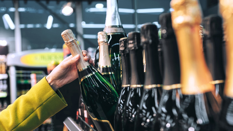 Hand reaching to select a champagne bottle