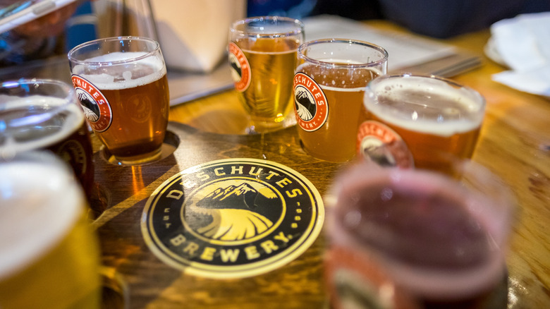 Flight-style beer glasses on tray with Deschutes Brewery logo.