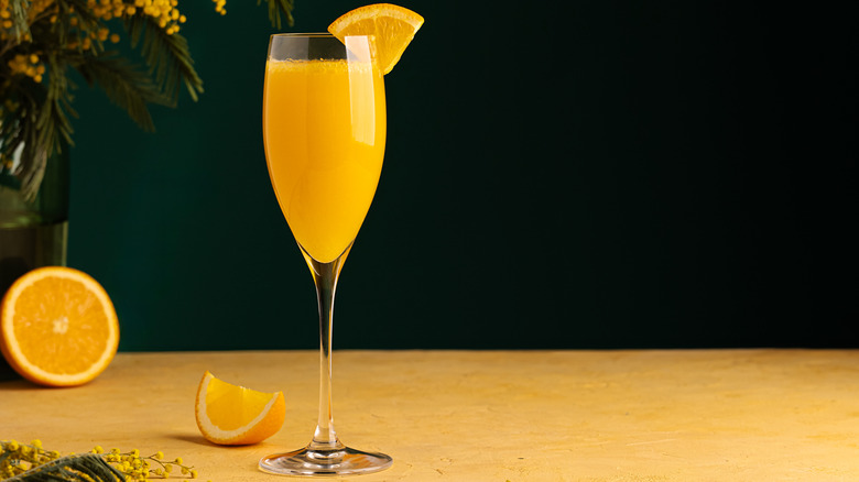 A mimosa in a champagne flute garnished with an orange slice