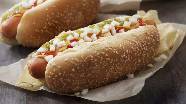 Hot dogs topped with condiments and onions.