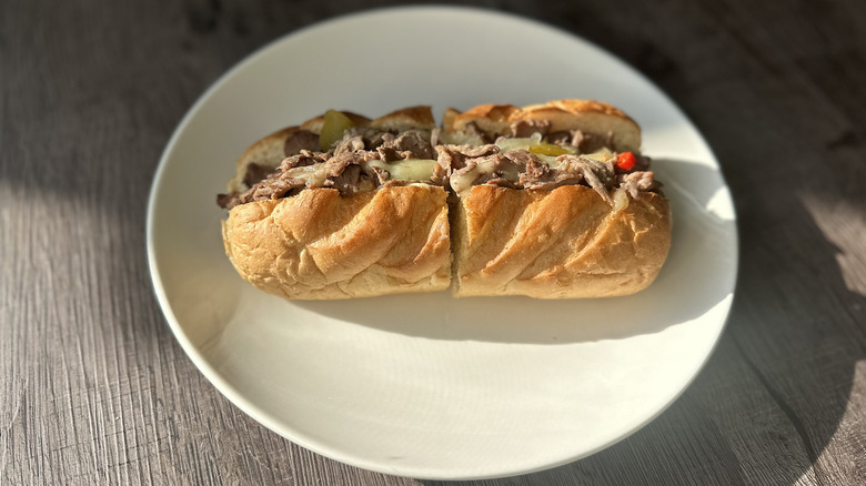 Firehouse cheesesteak sub on white plate.