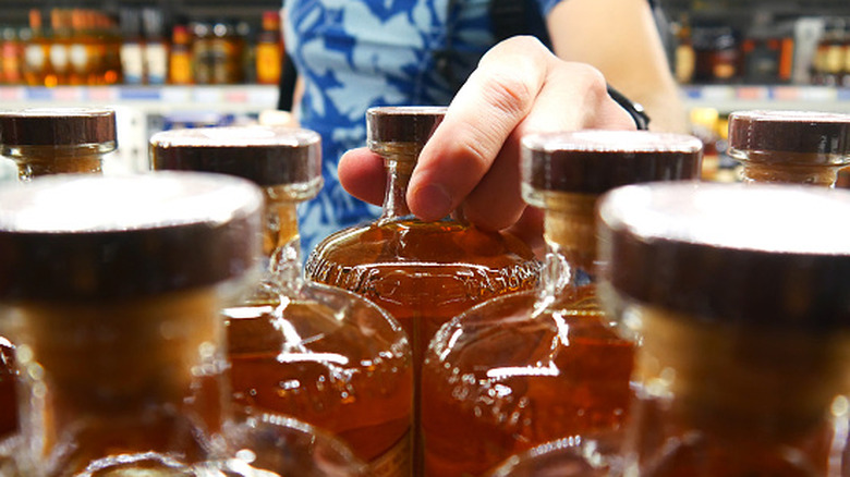 Woman's hand grabbing a bourbon bottle off the shelf