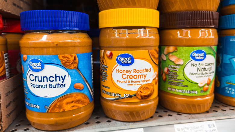 Various jars of Great Value peanut butter on store shelf.