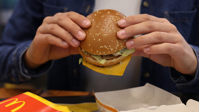 A person holding a McDonald's hamburger with both hands