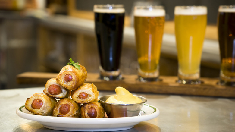 pigs in a blanket on plate with beer flight in background
