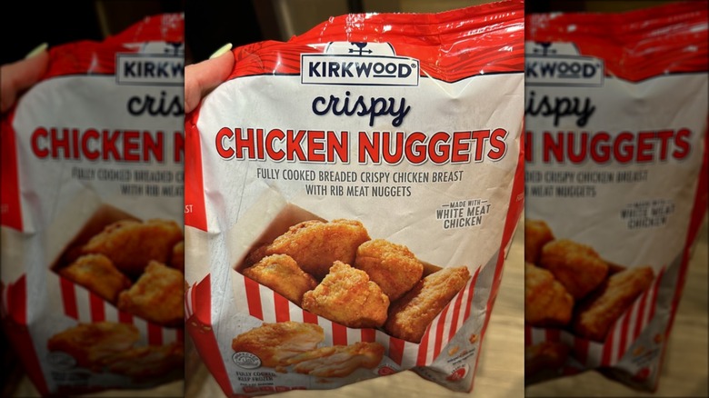 A hand holds up a bag of Kirkwood crispy chicken nuggets