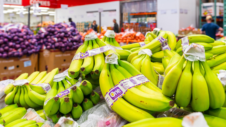 A pile of bunched green bananas on display in the produce section at Costco