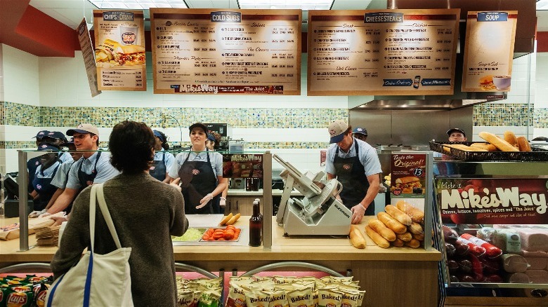 Counter at a Jersey Mike's shop with employees behind it and one customer