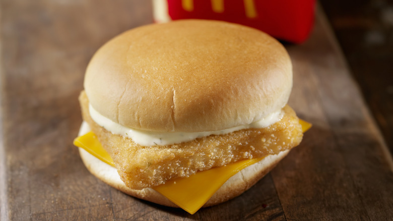 Closeup of a McDonald's Filet-O-Fish sandwich with cheese and tartar sauce placed on a wooden table