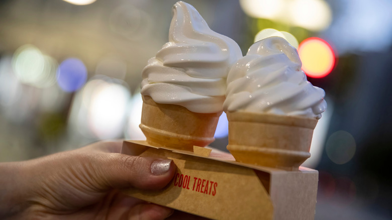 A hand holding two cones with McDonald's soft serve ice cream