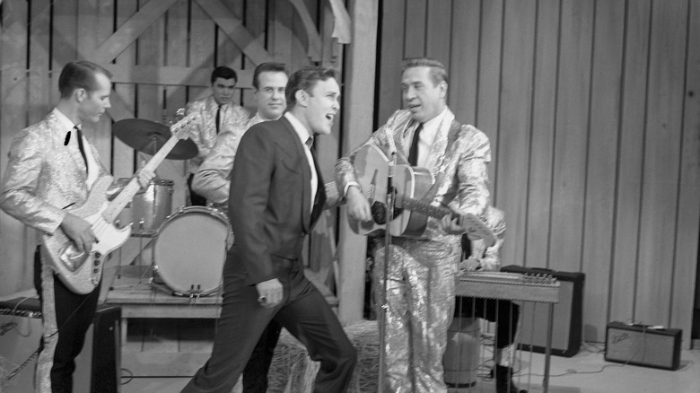 Black and white photo of Jimmy Dean performing on set of The Jimmy Dean Show with Buck Owens and His Buckaroos
