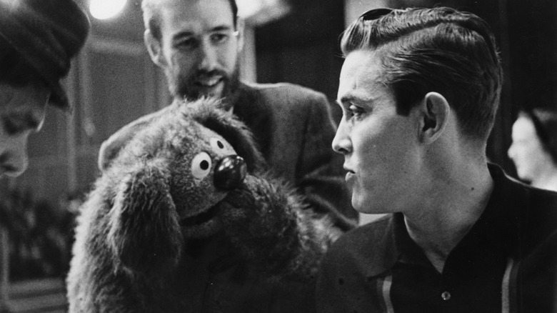 Black and white, behind the scenes photo of Jimmy Dean and the hand puppet Rowlf the Dog from The Muppets