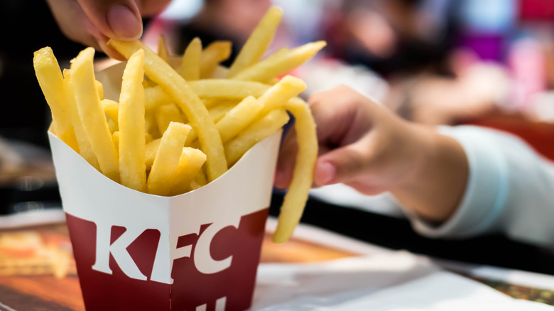 child's hand reaching for french fries