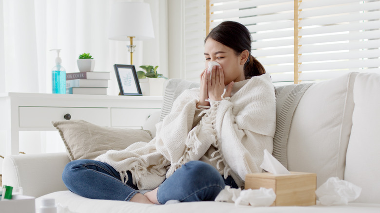 Person sitting a couch blowing their nose