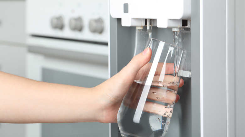 person filling glass with water