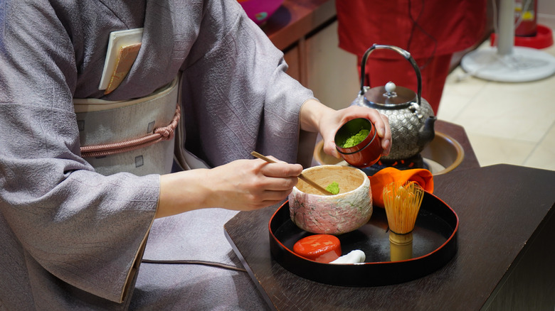 woman in kimono preparing matcha for tea ceremony