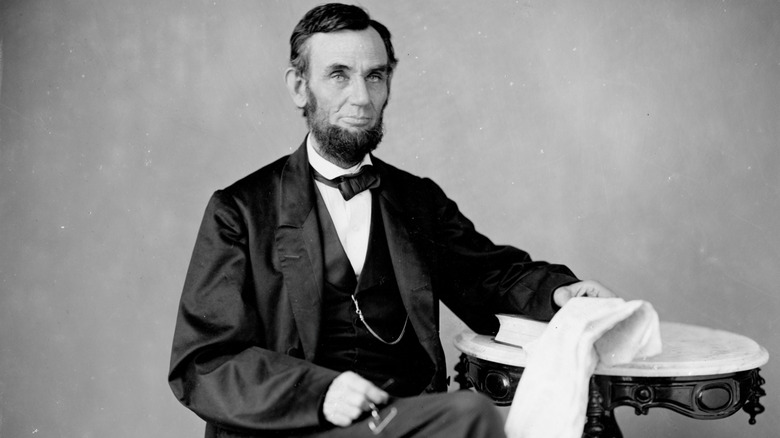 Abraham Lincoln sitting at a table with a book and towel.