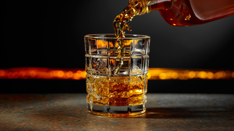 Whiskey pouring from bottle into glass.