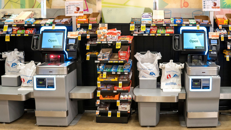 Gray and black self-checkout registers surrounded by candy inside a Safeway grocery store