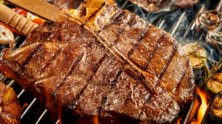   chuletón a la parrilla rodeado de verduras