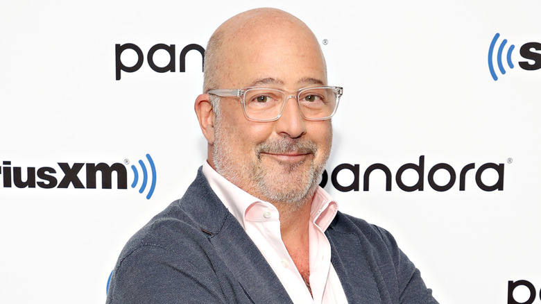 Andrew Zimmern smiles with glasses in close-up