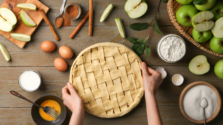 Unbaked apple pie next to raw ingredients