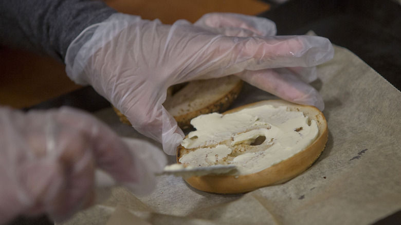 Spreading cream cheese on bagel