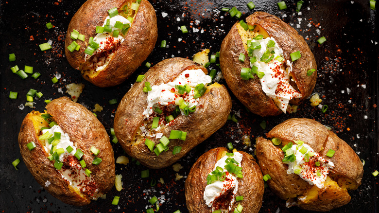 loaded baked potatoes on black background