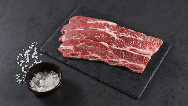 Raw short ribs with a bowl of salt