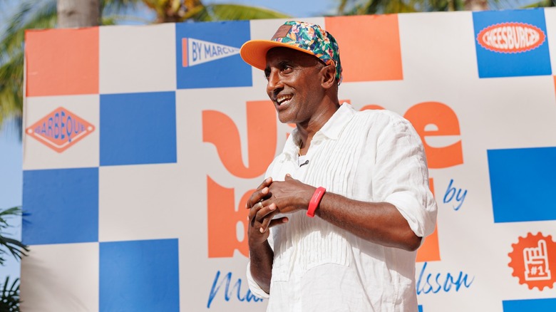 Chef Marcus Samuelsson posing in front of a Vibe BBQ sign