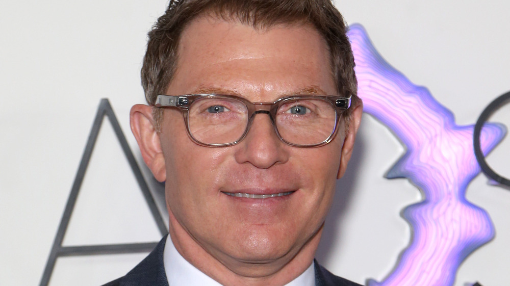 Bobby Flay wearing a gray suit and glasses