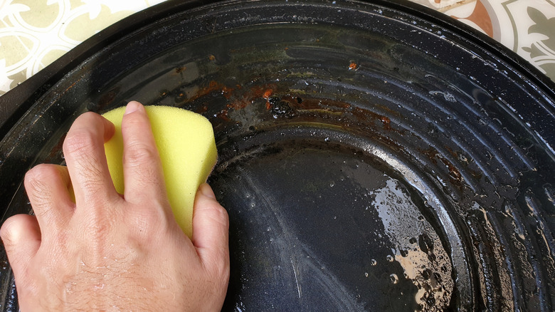 Person scrubbing a skillet with a sponge