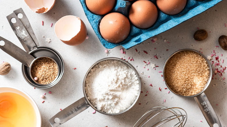 Flour, eggs, measuring cups, whisk, sugar and other baking ingredients