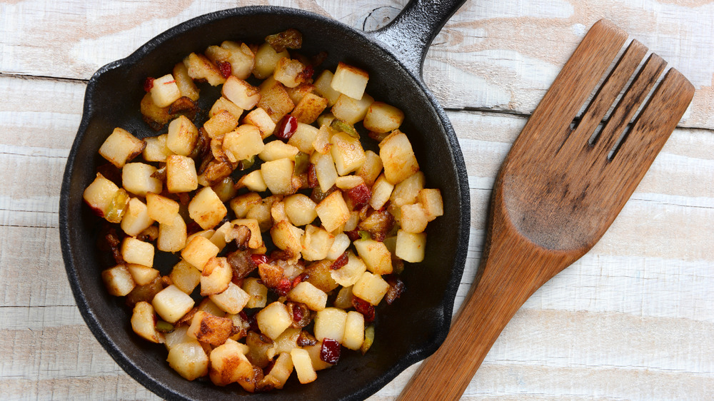 Breakfast potatoes being cooked in a cast iron skillet