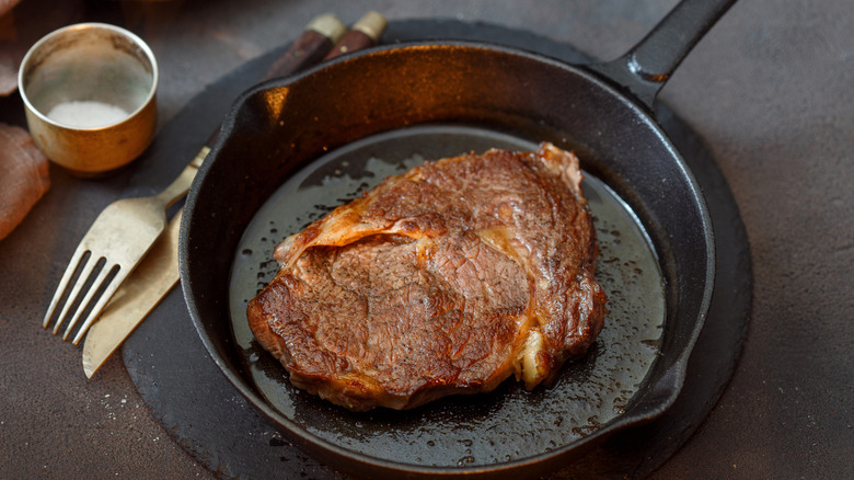 Steak cooking in a cast iron pan.