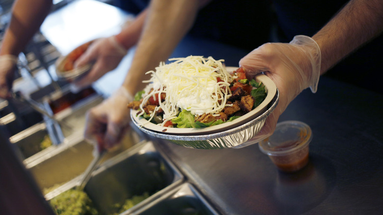 Chipotle employee prepares burrito bowl