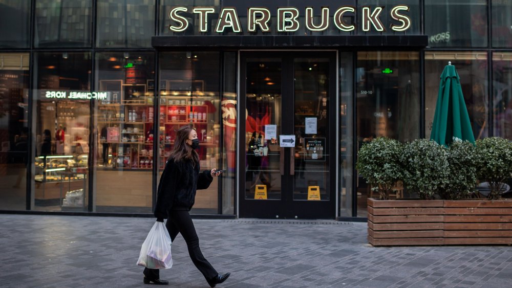 Woman in mask passes Starbucks