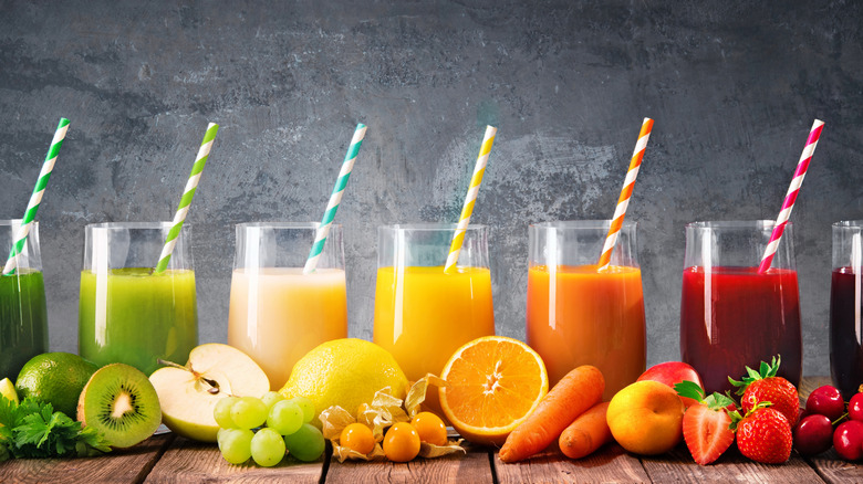 Different varieties of fruit juice in glasses with colorful straws