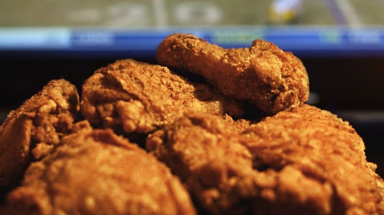 A pile of Culver's fried chicken in front of a blurred TV playing a sports game.