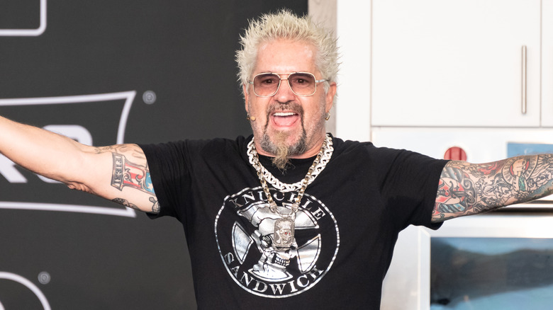 Guy Fieri in glasses and big silver chains around neck