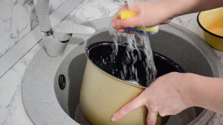 Person washing the inner pot of a slow cooker