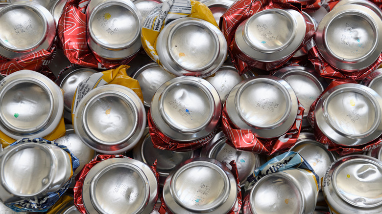 Bottoms of crushed beer cans, some with colored ink dots.