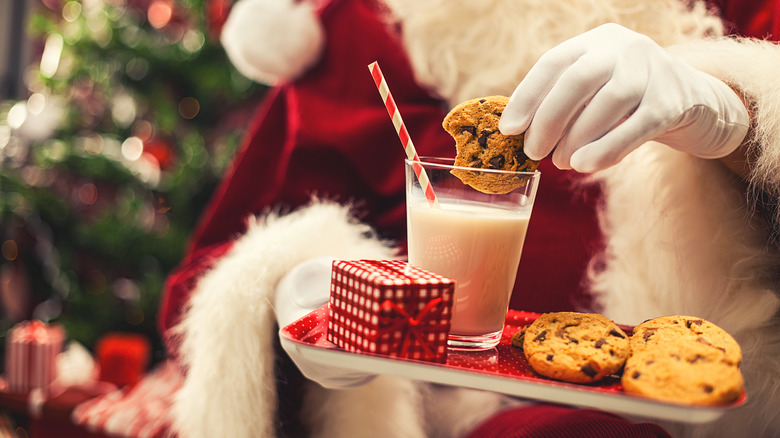 Santa Claus dunking cookie into glass of milk