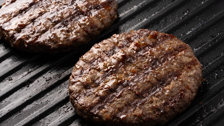 Closeup of two cooked hamburgers on a metal grill surface